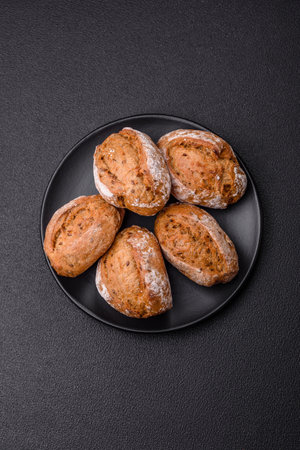 Fresh baked bread buns with salt, spices, seeds and grains on a dark backgroundの写真素材