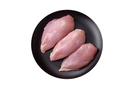 Fresh chicken fillet on a dark concrete table with spices and herbs. Preparation for cooking meat dishesの写真素材