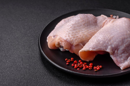 Fresh raw chicken thighs with salt and spices on dark concrete backgroundの写真素材