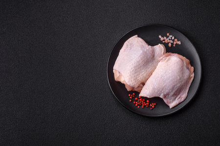 Fresh raw chicken thighs with salt and spices on dark concrete backgroundの写真素材
