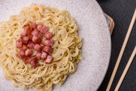 Delicious Asian dish rice noodles or udon with vegetables, spices and herbs on a dark concrete backgroundの写真素材