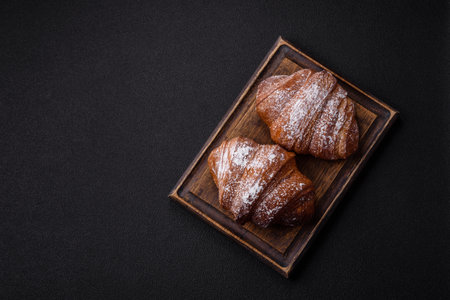 Delicious fresh sweet crispy croissant with chocolate on dark concrete backgroundの写真素材