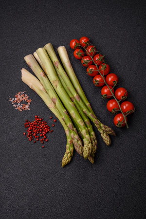 Sprigs of raw green asparagus as an ingredient for preparing a healthy breakfast on a dark concrete backgroundの写真素材