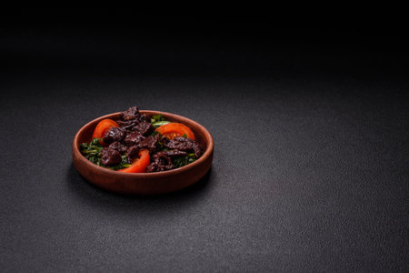 Delicious warm salad of chicken liver, spinach, arugula, tomatoes with salt, spices and herbs on a dark concrete backgroundの写真素材