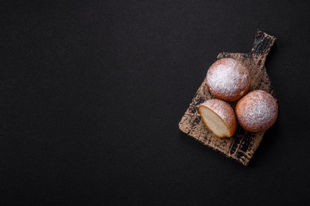 Round homemade cheese donuts glazed with citrus flavor on a dark concrete background