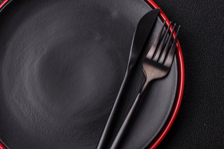 Empty ceramic round plate on dark textured concrete background. Cutlery, preparation for dinnerの写真素材