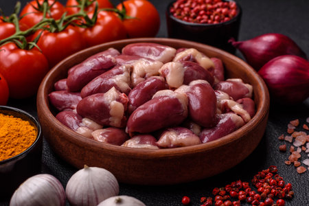 Raw chicken hearts with salt, spices and herbs on a dark concrete backgroundの写真素材
