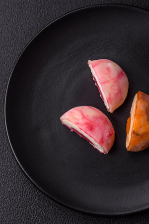 Delicious colorful asian mochi sweets with rice dough shell and fruit filling on dark concrete backgroundの写真素材