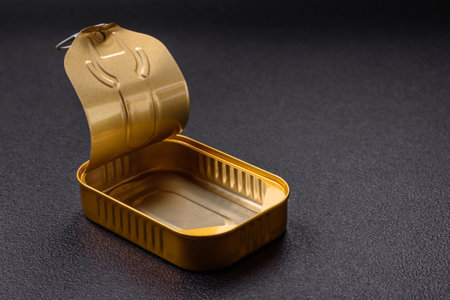 Tin or aluminum opened rectangular can of canned food with a key on a dark concrete background