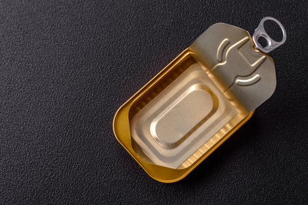 Tin or aluminum opened rectangular can of canned food with a key on a dark concrete backgroundの写真素材