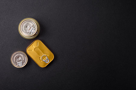 Metal can with canned meat or fish with a key to open it on a dark concrete backgroundの写真素材