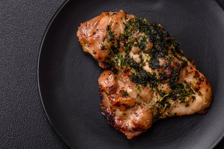 Grilled boneless chicken thigh with salt, spices and herbs on a dark concrete backgroundの写真素材