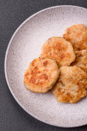 Delicious fresh fried minced fish cutlets with spices and herbs on a dark concrete background