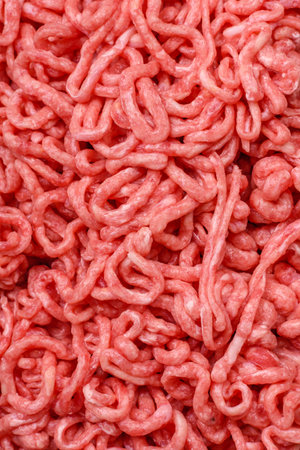 Fresh raw ground beef with salt and spices on dark concrete background