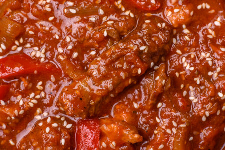 Thai Asian dish with meat, hot pepper, tomato sauce and sesame on dark concrete backgroundの写真素材