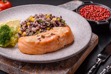 A piece of salmon with rice, broccoli, salt and spices on a dark concrete backgroundの写真素材