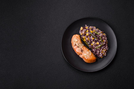 A piece of salmon with rice and vegetables on a dark backgroundの写真素材