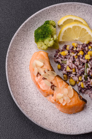 A piece of boiled salmon with rice, broccoli, salt and spices on a dark concrete backgroundの写真素材