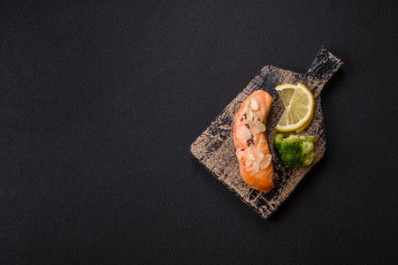 A piece of salmon with broccoli, salt and spices on a dark concrete backgroundの写真素材