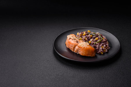 A piece of salmon with rice and vegetables on a dark backgroundの写真素材