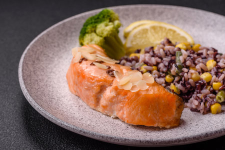 A piece of salmon with rice, broccoli, salt and spices on a dark concrete backgroundの写真素材