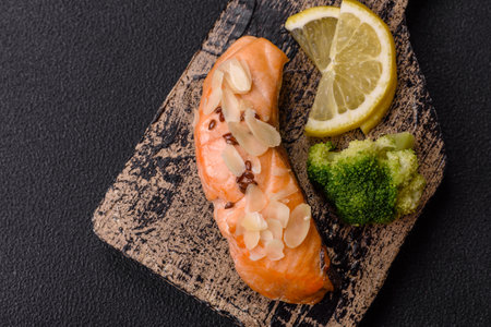 A piece of boiled salmon with rice, broccoli, salt and spices on a dark concrete backgroundの写真素材