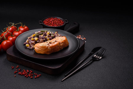 A piece of boiled salmon with rice, broccoli, salt and spices on a dark concrete backgroundの写真素材