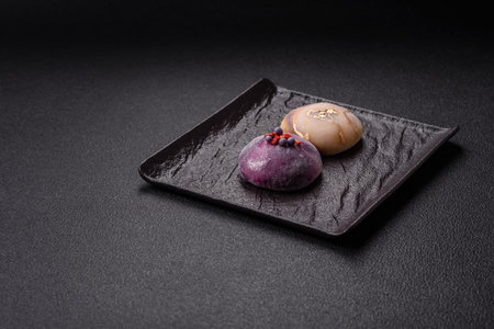 Delicious cold Japanese mochi dessert with colorful rice dough shell and fruit filling on dark concrete backgroundの写真素材
