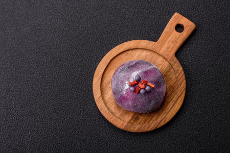Delicious cold Japanese mochi dessert with colorful rice dough shell and fruit filling on dark concrete backgroundの写真素材