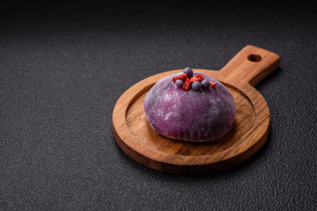 Delicious cold Japanese mochi dessert with colorful rice dough shell and fruit filling on dark concrete backgroundの写真素材