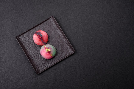 Delicious cold Japanese mochi dessert with colorful rice dough shell and fruit filling on dark concrete backgroundの写真素材