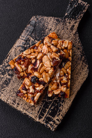Delicious sweet nutrition bars with nuts, dried berries gluten free on dark concrete background