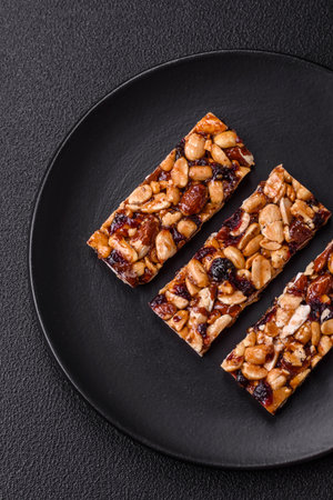 Delicious sweet nutrition bars with nuts, dried berries gluten free on dark concrete background
