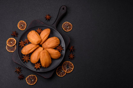 Traditional French madeleine biscuits with nutty flavor on a dark concrete background