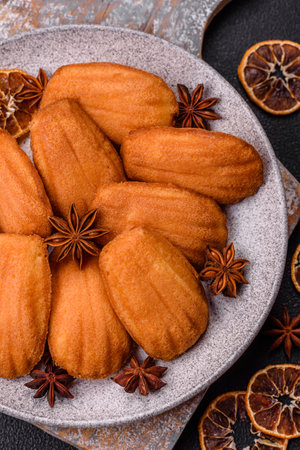 Traditional French madeleine biscuits with nutty flavor on a dark concrete background