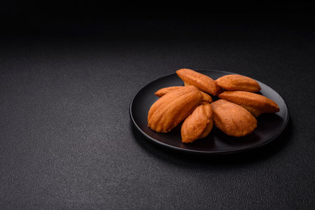 Traditional French madeleine biscuits with nutty flavor on a dark concrete backgroundの写真素材