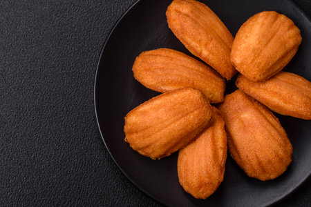 Traditional French madeleine biscuits with nutty flavor on a dark concrete backgroundの写真素材