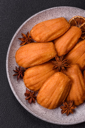 Traditional French madeleine biscuits with nutty flavor on a dark concrete background