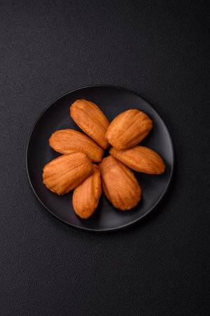 Traditional French madeleine biscuits with nutty flavor on a dark concrete backgroundの写真素材