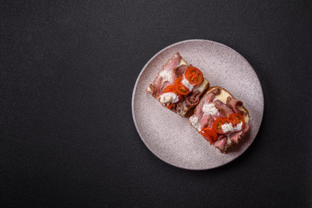 Sandwich with brioche bun, roast beef, tomatoes, stracciatello and vitello tonato sauceの写真素材