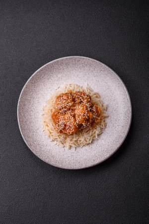 Asian food with rice and meat with sweet and sour sauce, spices and herbs on a dark concrete backgroundの写真素材