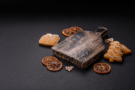 Empty wooden cutting board with copy space with gingerbread cookies and Christmas decor on dark...