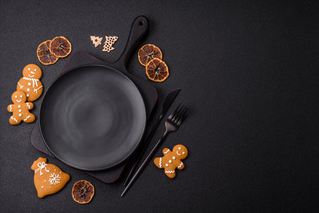 Empty round ceramic copy space plate with gingerbread cookies and Christmas elements on a dark textured backgroundの写真素材
