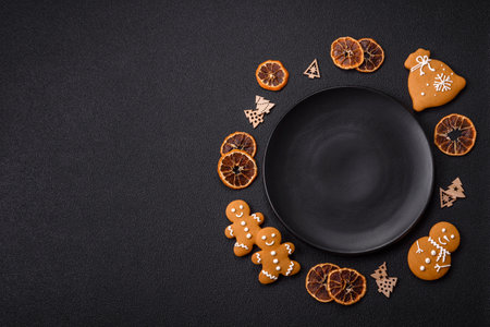 Empty round ceramic copy space plate with gingerbread cookies and Christmas elements on a dark textured backgroundの写真素材