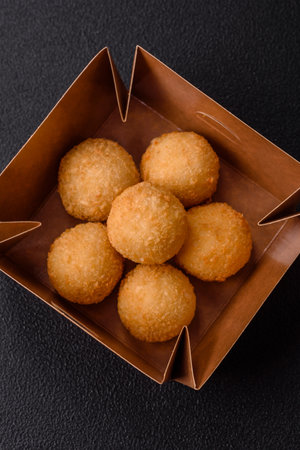 Fast food cheese balls breaded with salt and spices on a dark concrete background