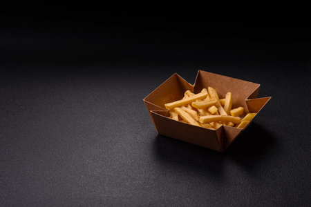 Fast food French fries with salt and spices on a dark concrete background