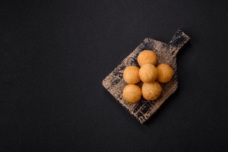Cheese balls breaded with salt and spices on a dark concrete background