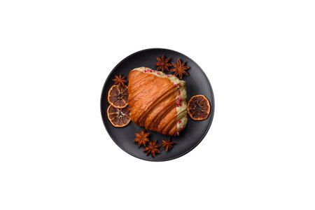 Crispy sweet red croissant with pistachio, raspberry and strawberry on a dark concrete backgroundの写真素材