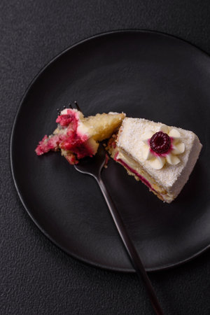 Sweet delicious cake with a layer of raspberry jam sprinkled with coconut on a dark concrete backgroundの写真素材