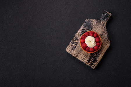 Sweet tartlet with raspberries and cream on a dark textured backgroundの写真素材